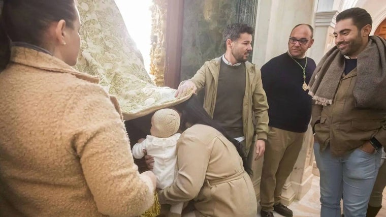 Un bebé pasa bajo el manto de la Virgen del Rocío