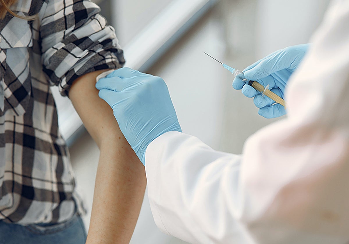 Un sanitario vacuna a un menor en una imagen de archivo