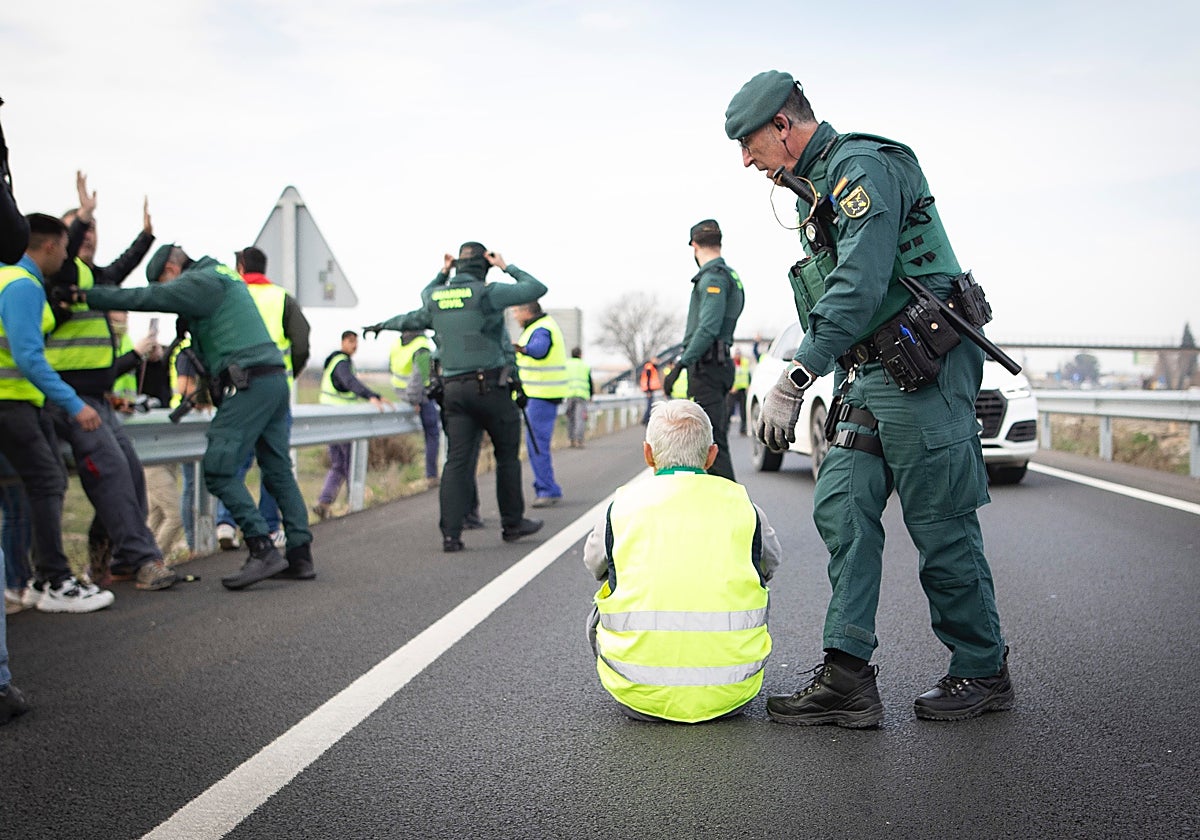 Un agente conmina a levantarse a un manifestante sentado en la vía de servicio contigua a la autovía