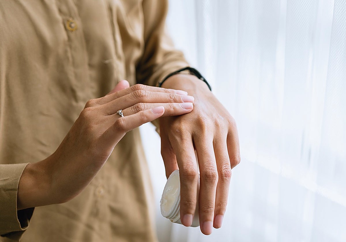 Una mujer se echa crema en las manos