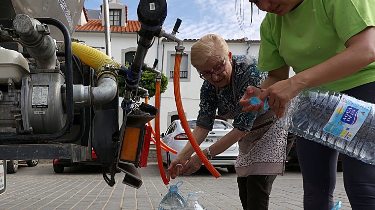 Dos personas toman agua de un camión cisterna en el Norte