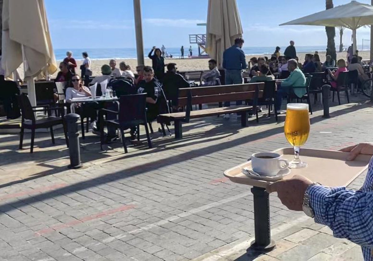 Imagen de archivo de un camarero sirviendo mesas en la terraza de un restaurante