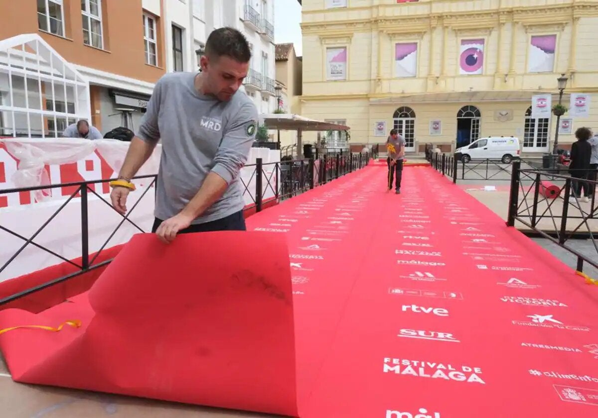 Un operario despliega la alfombra roja a las puertas del Teatro Cervantes en la edición de 2023