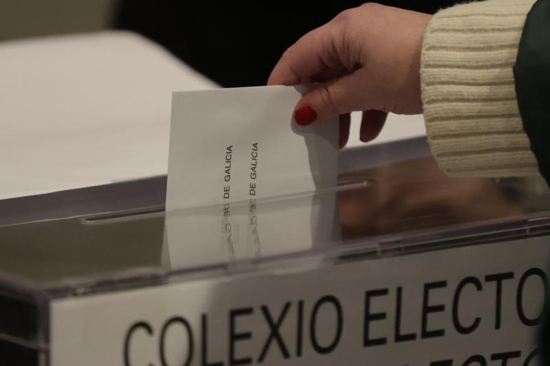 Primeros votantes introducen su papeleta en la urna de las mesas electorales instaladas en el Pazo de María Pita, Casa del Concello de A Coruña