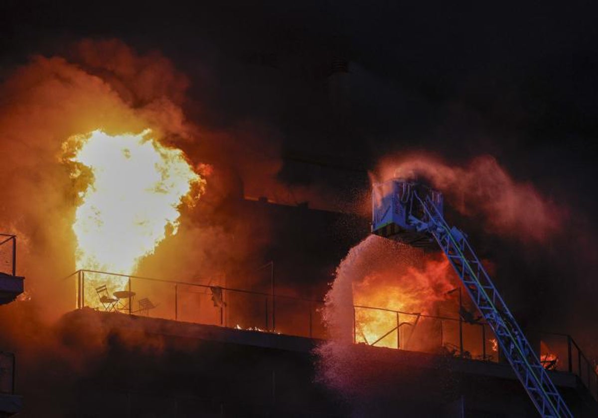 Bomberos trabajan en el incendio declarado sobre las cinco y media de esta tarde en un quinto piso de un edificio de viviendas de Valencia que ha afectado totalmente al inmueble y se ha propagado a otro anexo