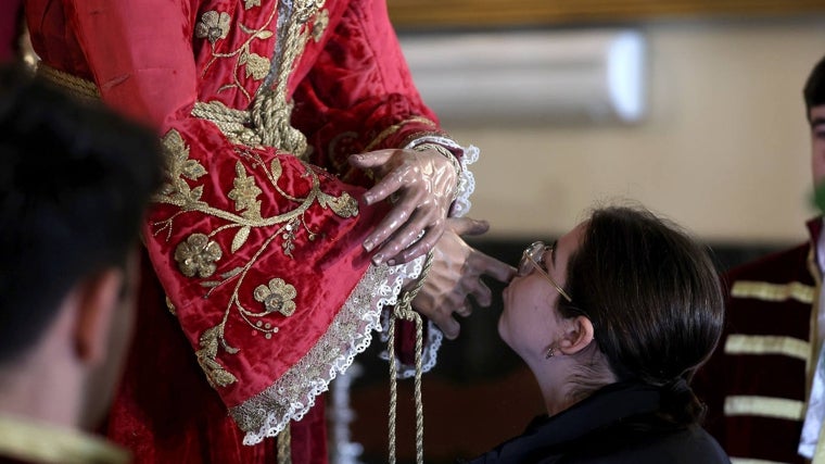 Una joven besa la mano de Nuestro Padre Jesús, Divino Salvador, en su Prendimiento