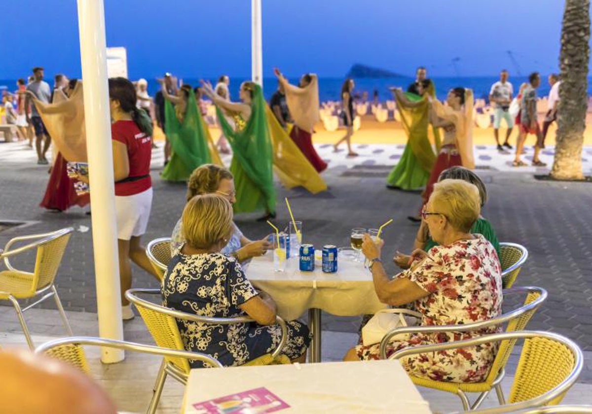 Turistas jubiladas en la terraza de un bar en la Playa de Levante de Benidorm, de noche.