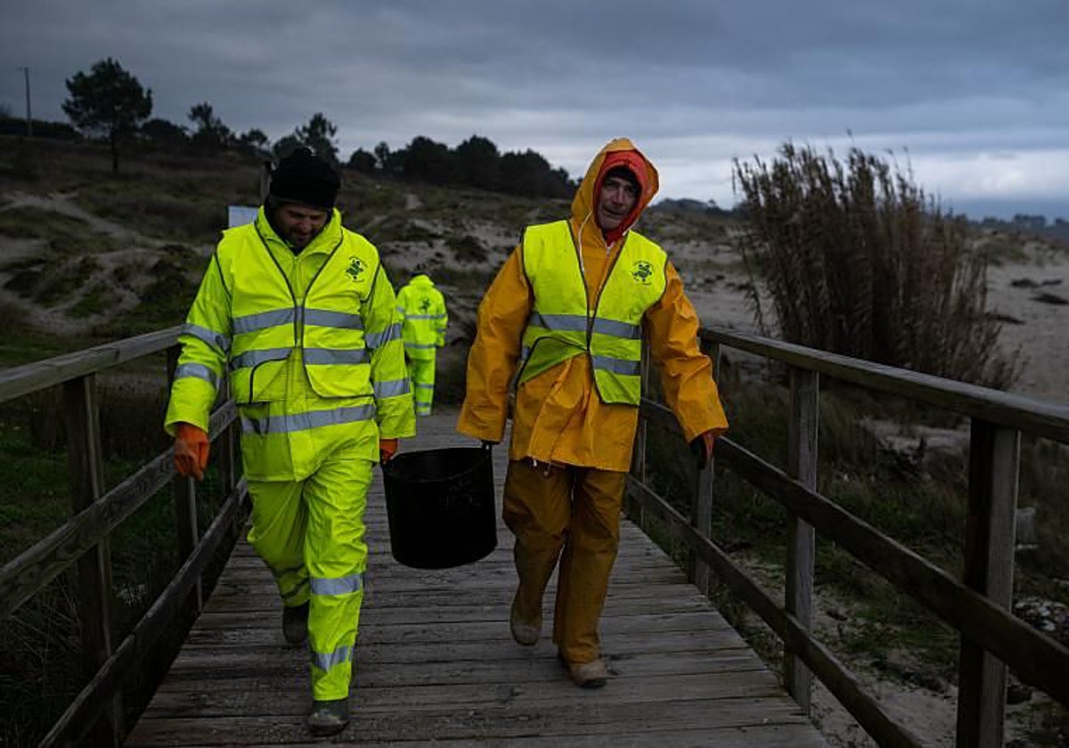 Dos hombres cargan un cubo de pélets, en enero, en Queiruga (La Coruña)