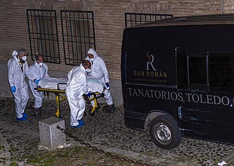 Imagen secundaria 1 - Miembros de los servicios funerarios trasportan uno de los cuatro cadáveres encontrados este martes en la calle Santa Leocadia de Toledo