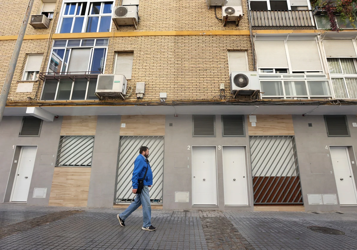 Un vecino camina delante de una hilera de apartamentos en el barrio de La Viñuela