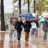 Turistas con paraguas en el paseo marítimo de Marbella
