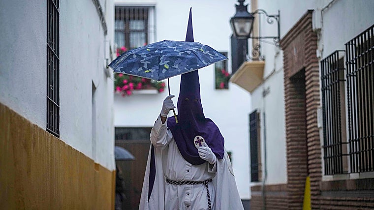 Nazareno bajo un paraguas en una calleja de Córdoba