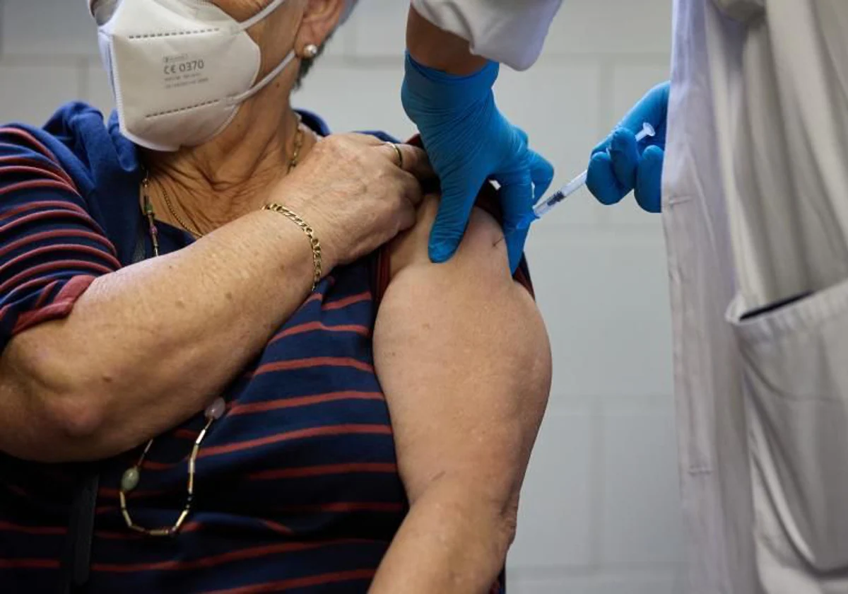 Una sanitaria administra una vacuna a una residente en un centro de mayores