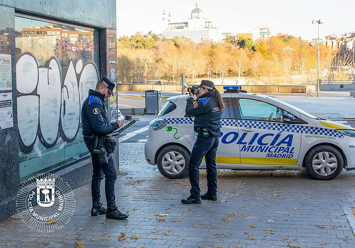 Dos agentes de la Sepropur fotografían una pintada en Madrid