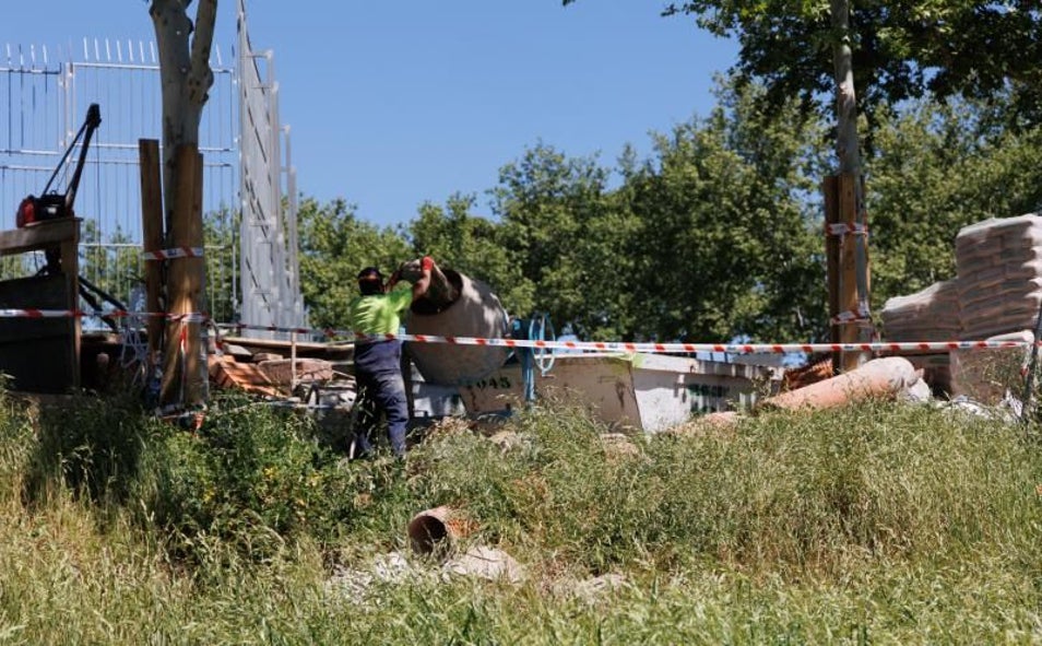 Imagen principal - Sobre estas líneas y a la izquierda, los obreros trabajando esta semana para tapar el socavón, que alcanza los 4 metros de diámetro. Abajo, una bomba que extrae el agua para vertirla en la alcantarilla