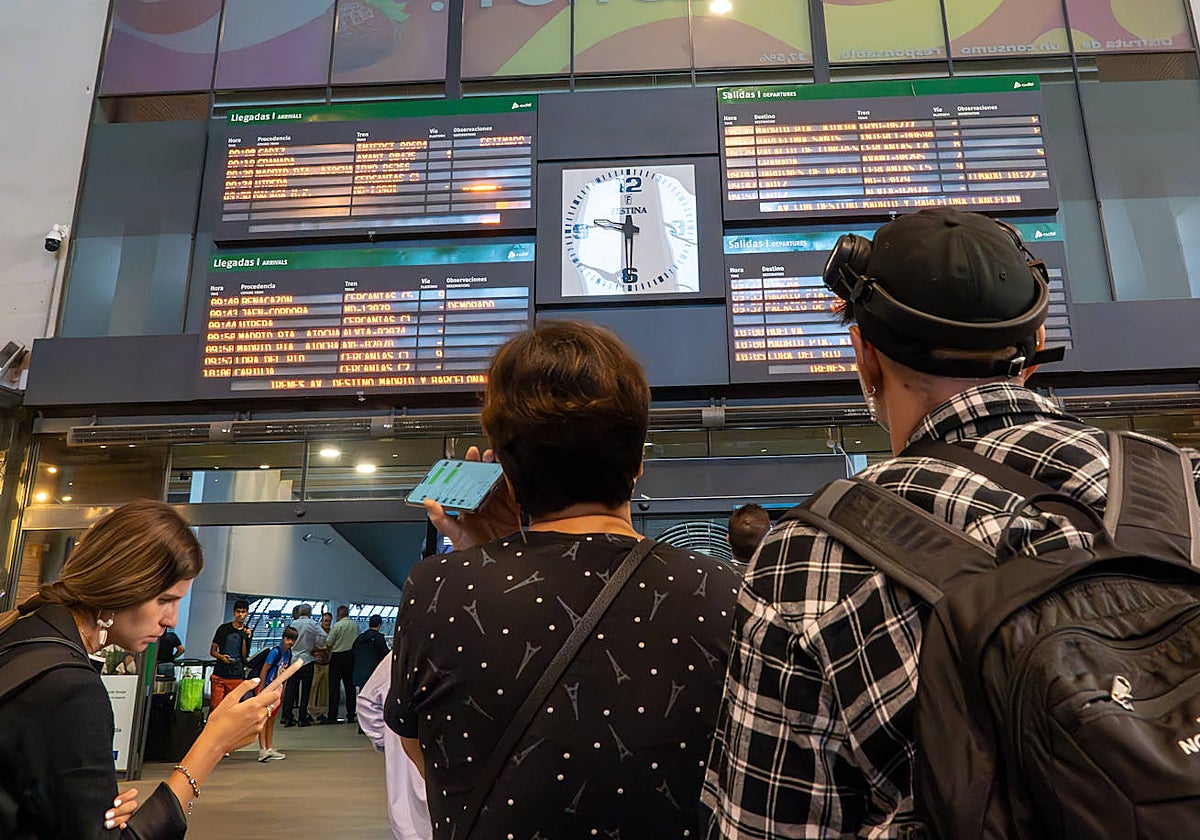 Dos pasajeros consultan las llegadas de AVE en la estación de Santa Justa