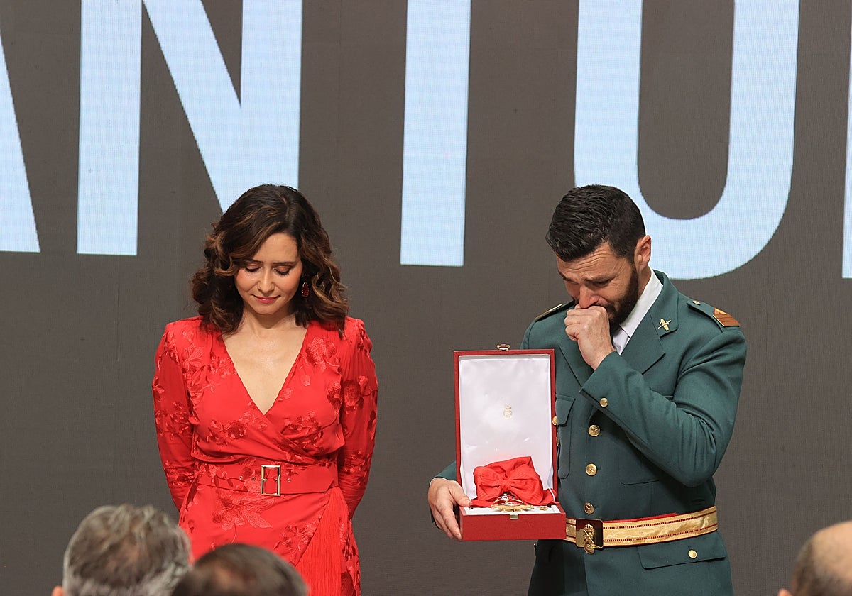 Un cabo primero de la guardia civil compañero del fallecido la semana pasada recoge la condecoración visiblemente emocionado, junto a Isabel Díaz Ayuso