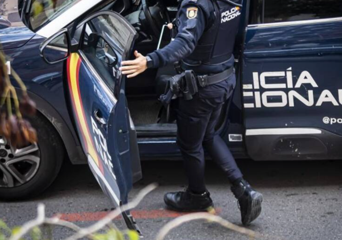 Agente de la Policía Nacional subiendo a un vehículo policial en foto de archivo