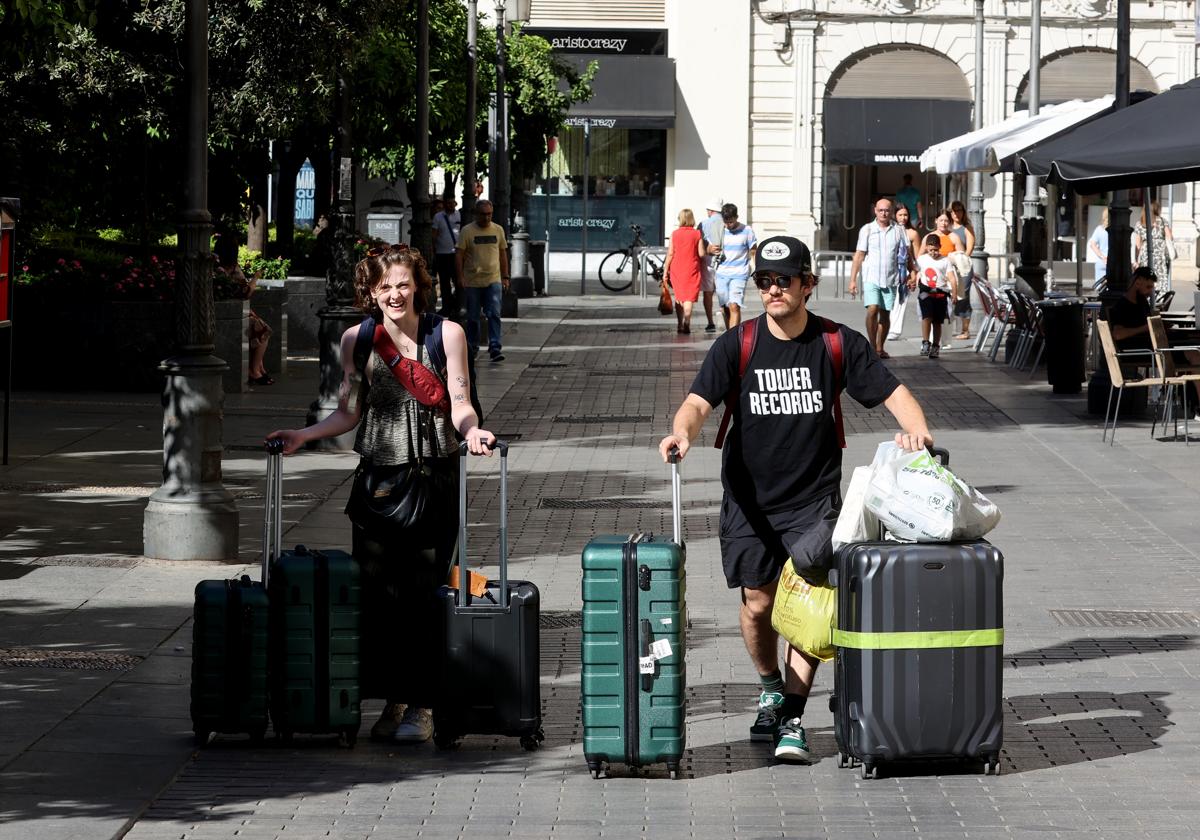 Dos turistas llevando sus maletas por la plaza de las Tendillas