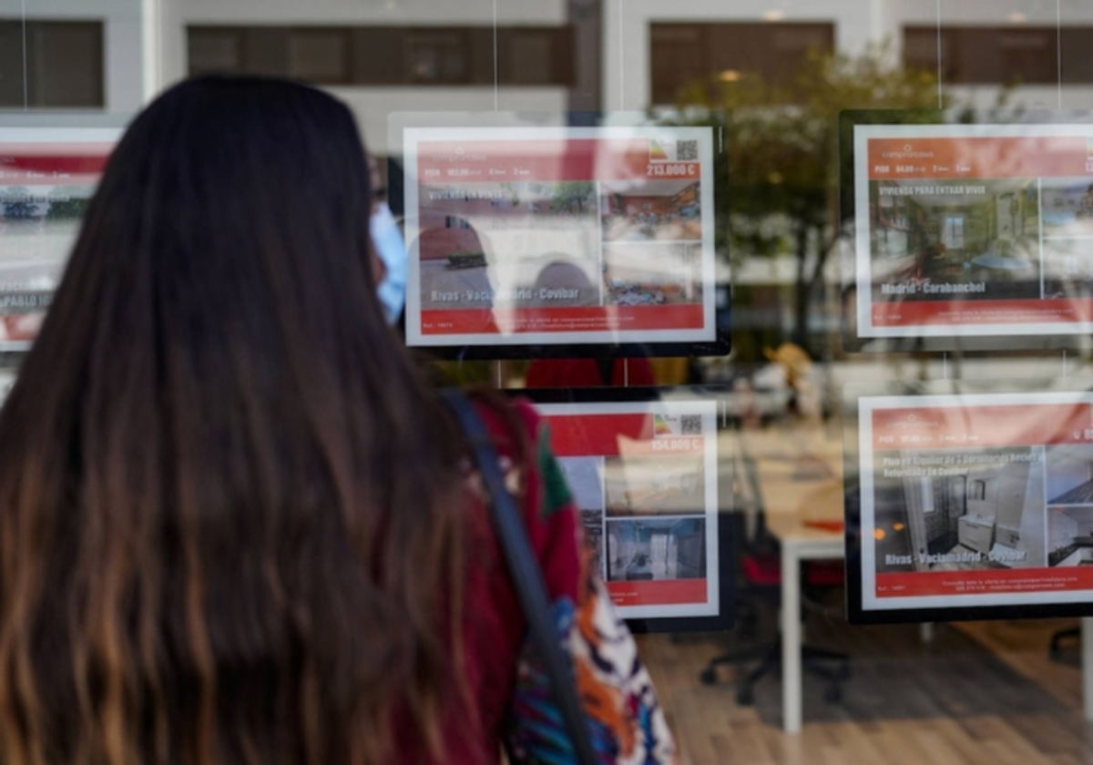 Una joven frente al escaparate de una inmobiliaria