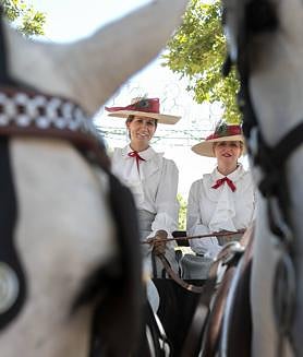 Imagen secundaria 2 - Arriba, Andrew Pocrid con sus modelos; debajo, una caseta llena durante el mediodía de este sábado y a la derecha, dos mujeres sobre un carruaje de tradición