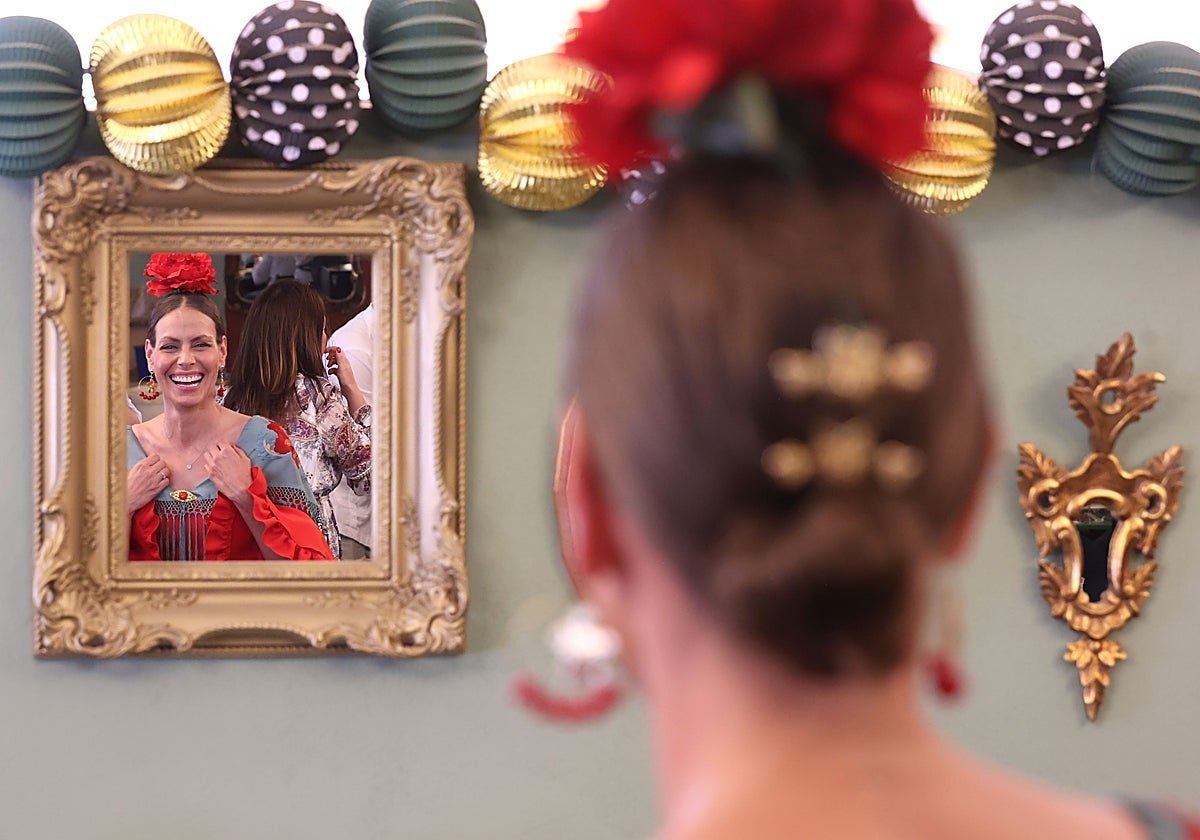 Una mujer vestida de flamenca se refleja en un espejo en la Feria de Córdoba