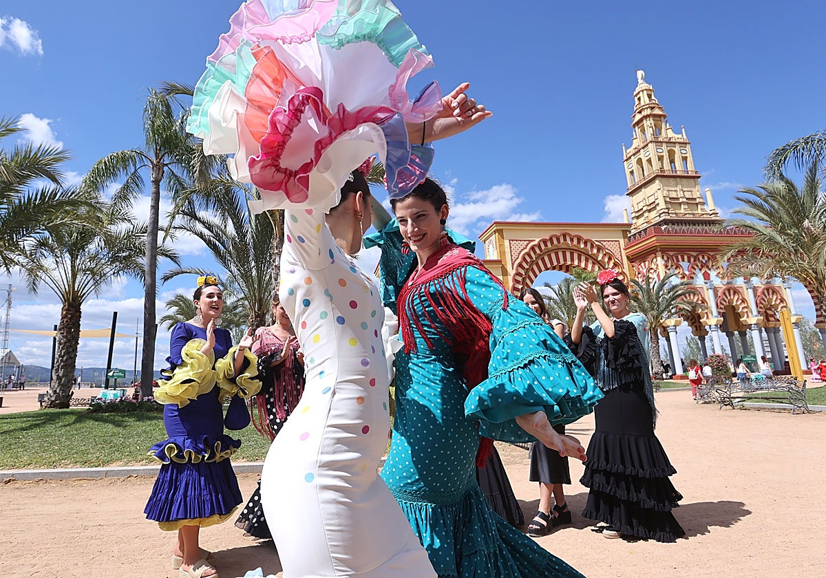 Dos mujeres bailan sevillanas junto a la portada de la Feria de Córdoba