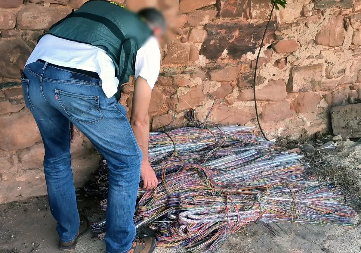 Agente de la Guardia Civil junto a montones de cable de telefonía recuperados tras un robo similar, en una imagen de archivo
