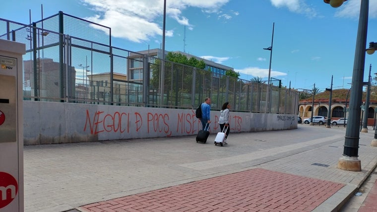 Dos turistas pasean frente una pintada contra los apartamentos turísticos bajo el lema «Negocios de pocos, miseria de muchos» en Valencia