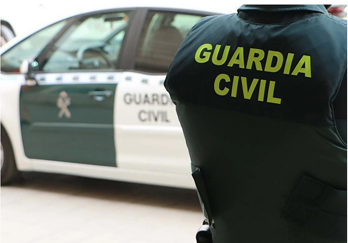 Un agente del Instituto Armado junto a un coche patrulla