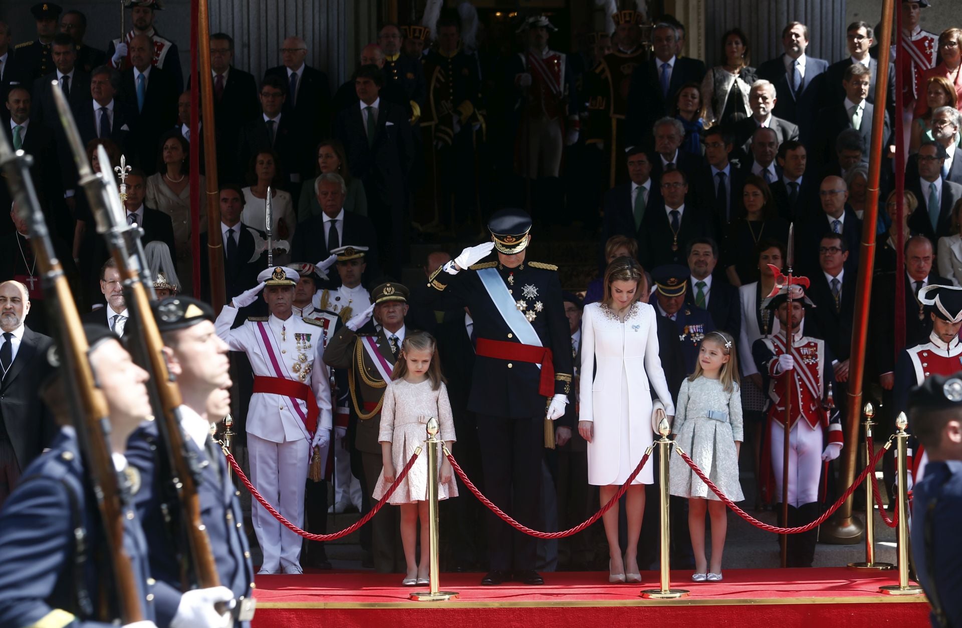 Desde la escalinata de la Puerta de los Leones y en posición de firmes, los Reyes, junto a sus hijas, inclinaron la cabeza en señal de respeto, como marca el protocolo militar. Allí, Don Felipe le recordó, en un par de ocasiones, a la Princesa Leonor, situada a su derecha, que debía bajar la cabeza cuando la bandera de España pasase ante ellos. A su vez, el mismo estandarte se humilló por primera vez ante el nuevo Rey, un privilegio que sólo tiene el Jefe de Estado. A él se le dedicó el Himno Nacional en su versión larga y se dispararon 21 salvas de ordenanza en su honor.