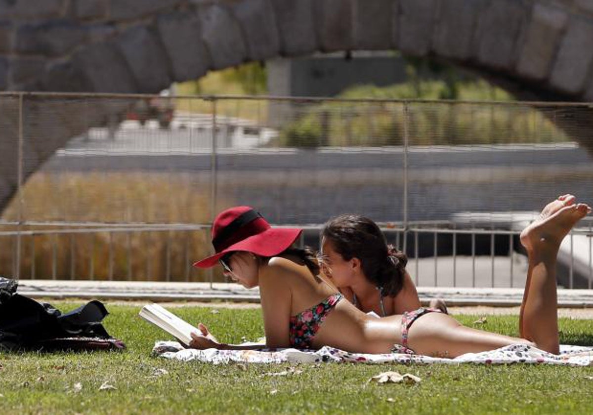 Dos jóvenes toman el sol en un parque de la capital