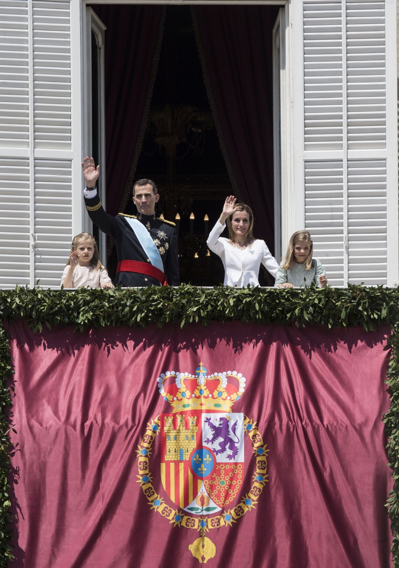 Llegada de los Reyes y de sus hijas, la Princesa Leonor y la Infanta Sofía, al balcón central del Palacio Real. Allí se pudo apreciar por primera vez el nuevo estandarte con el escudo de armas del nuevo monarca. Este presenta algunas disimilitudes con el de Don Juan Carlos. Don Felipe volvió a recuperar el carmesí, el color tradicional de la Monarquía española, a diferencia del azul que caracterizaba al de su predecesor. Desapareció el yugo y el haz de flechas, heredado de los Reyes Católicos, así como la Cruz de San Andrés o de Borgoña, símbolos que fueron reintroducidos durante el franquismo. El León, que representa a Castilla, pasó de ser rojo a ser morado. Por último, el símbolo de la granada, la fruta representativa del Reino de Granada, pasó a sus colores naturales, dejando atrás el dorado que engalanaba el estandarte de Don Juan Carlos.