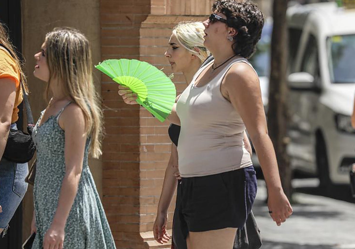 Varias personas caminan acaloradas en una calle de Sevilla