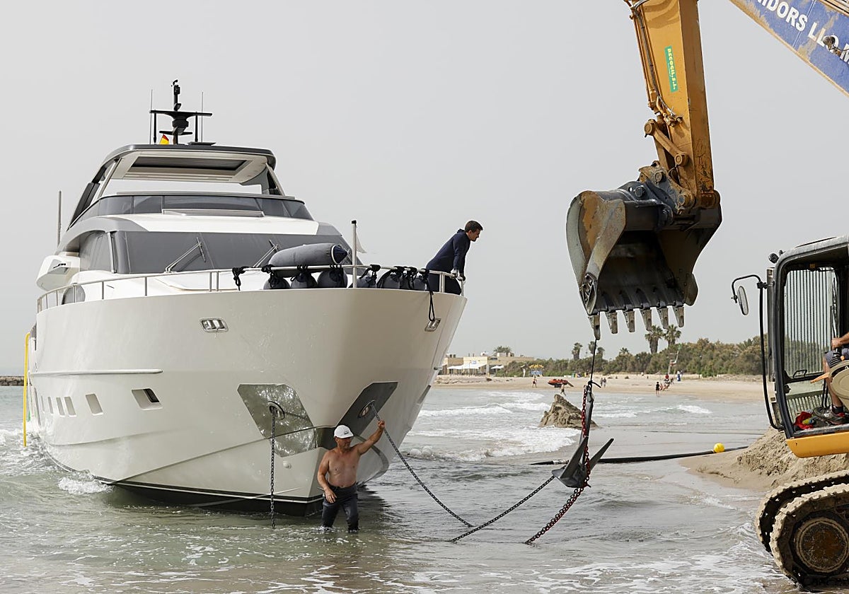 Un operario trabaja en el reflotamiento del yate varado en una playa de Valencia