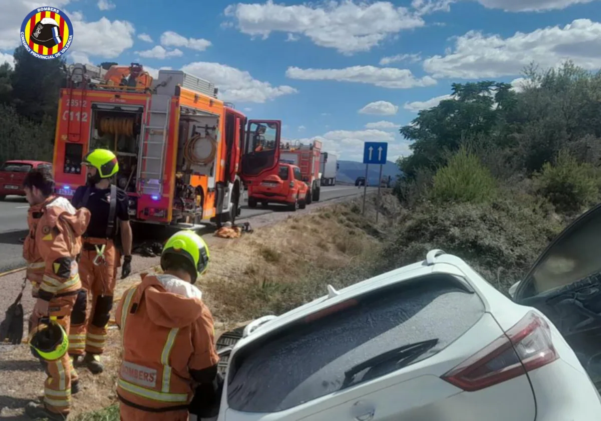 Bomberos junto al vehículo incendiado, tras el rescate.