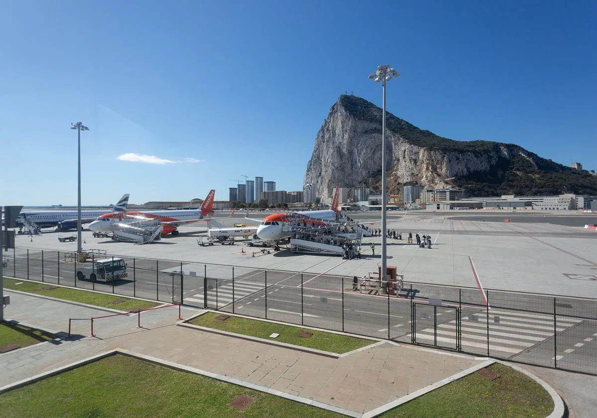 Varios aviones y pasajeros en la terminal de Gibraltar, con el Peñón al fondo