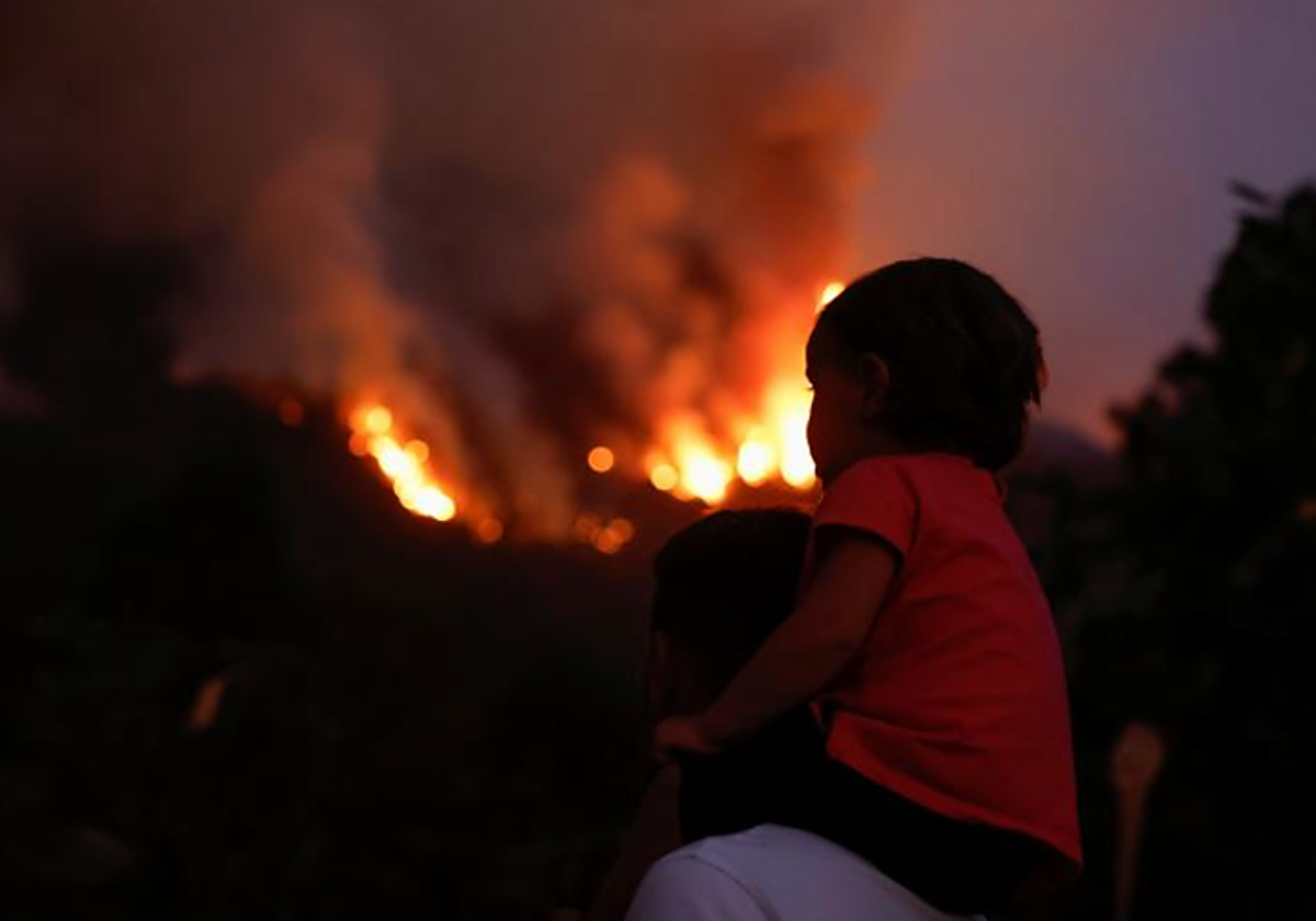 Un niño observa el incendio de Tenerife subido a hombros