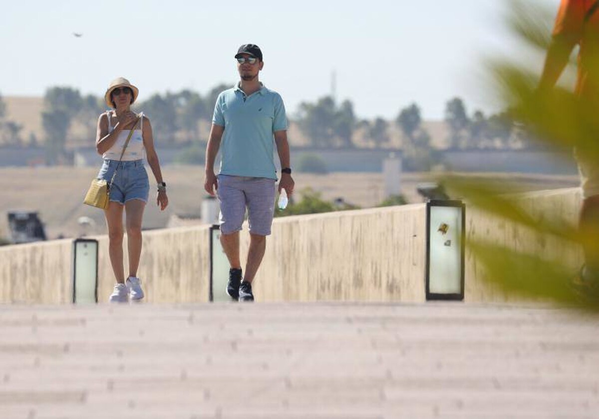 Dos turistas cruzan el Puente Romano en la capital cordobesa