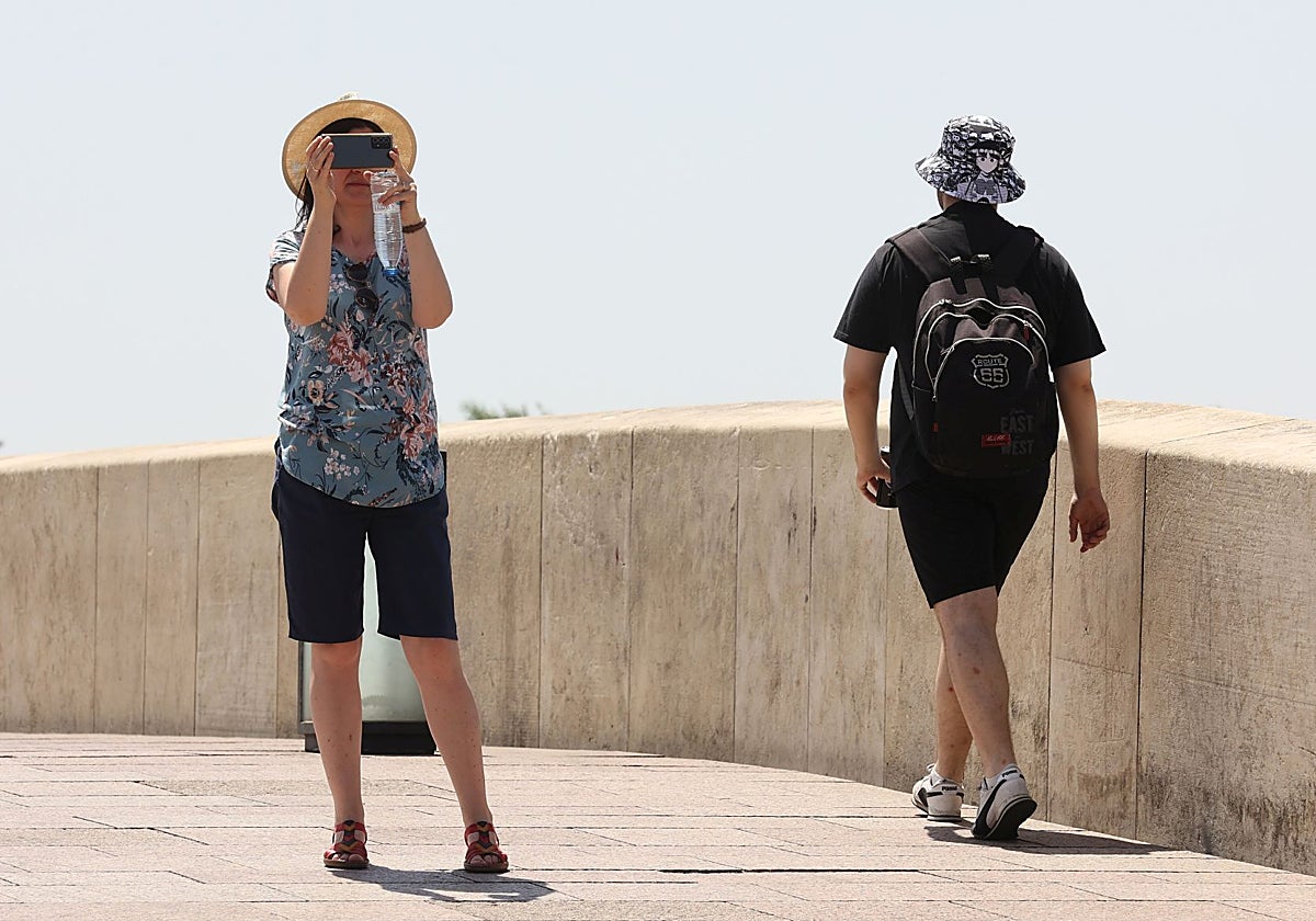 Dos turistas en el Puente Romano de Córdoba en un día de calor