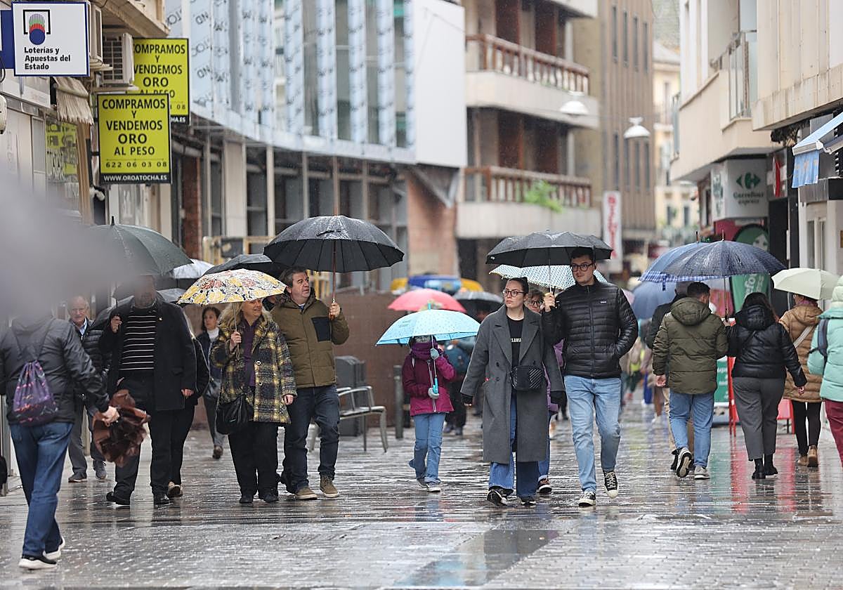 Varias personas paseando en febrero bajo la lluvia por la céntrica calle Jesús María