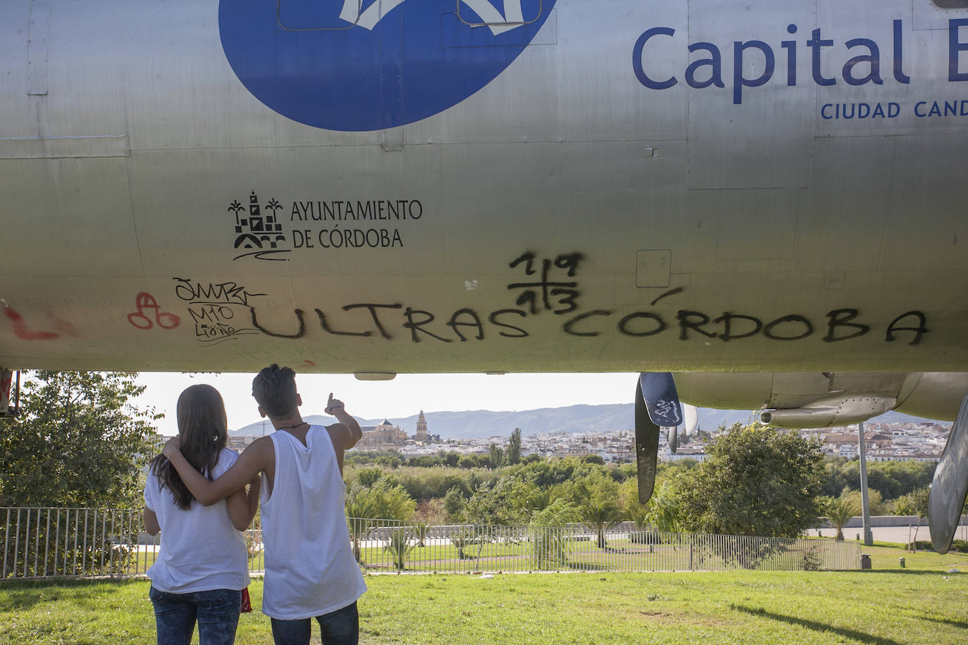 Dos jóvenes, en 2015, observando pintadas en el avión cultural