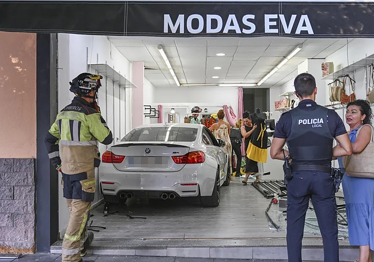 Eva, la propietaria de la tienda, junto a un policía local, y el coche dentro del local.