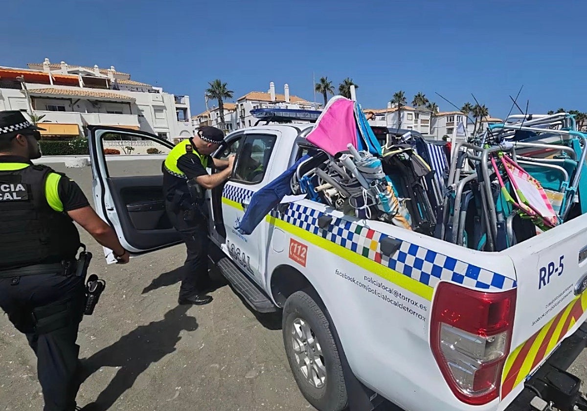 Agentes de la Policía Local retiran sillas y sombrillas en una playa de Torrox