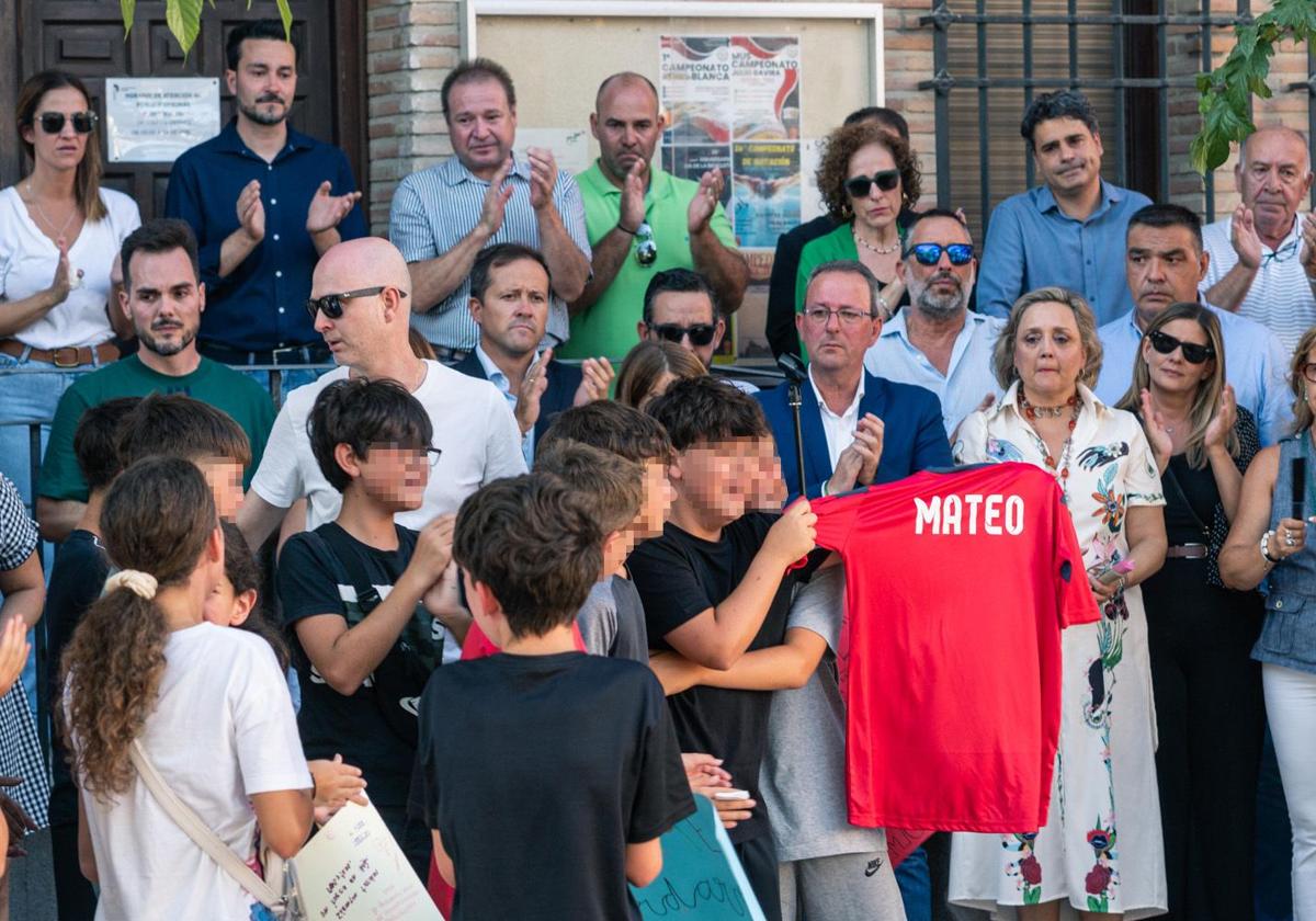 Amigos del niño asesinado muestran una camiseta con su nombre, durante el minuto de silencio