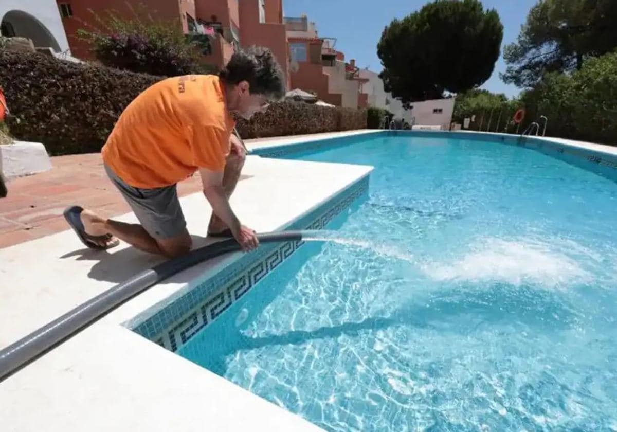 Un operario llena una piscina privada de una urbanización