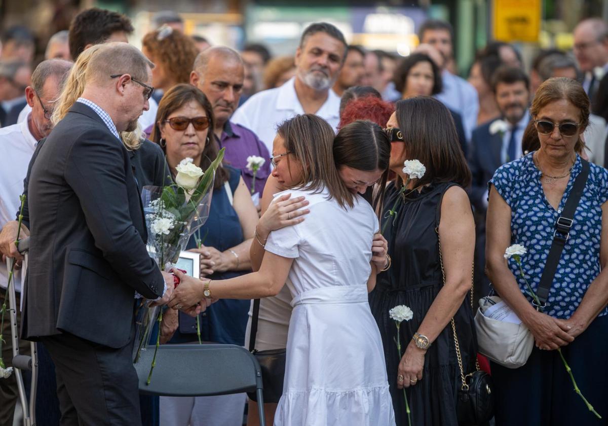 Varias personas participan en una ofrenda floral durante el acto en homenaje a las víctimas del atentado del 17A