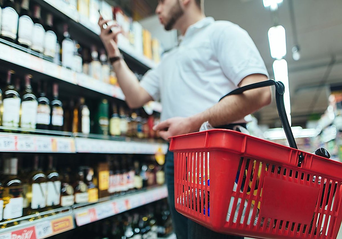 Un consumidor compara los precios de vinos en un estante de un supermercado