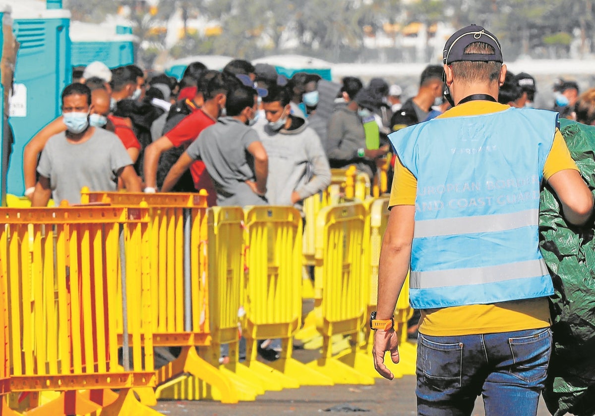 Agente de Frontex junto a decenas de inmigrantes en Canarias en 2020