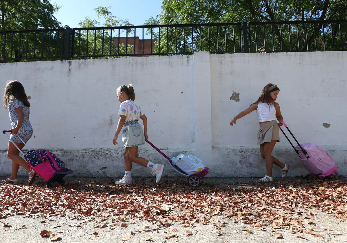 Tres escolares tiran de sus mochilas de camino al colegio en Córdoba